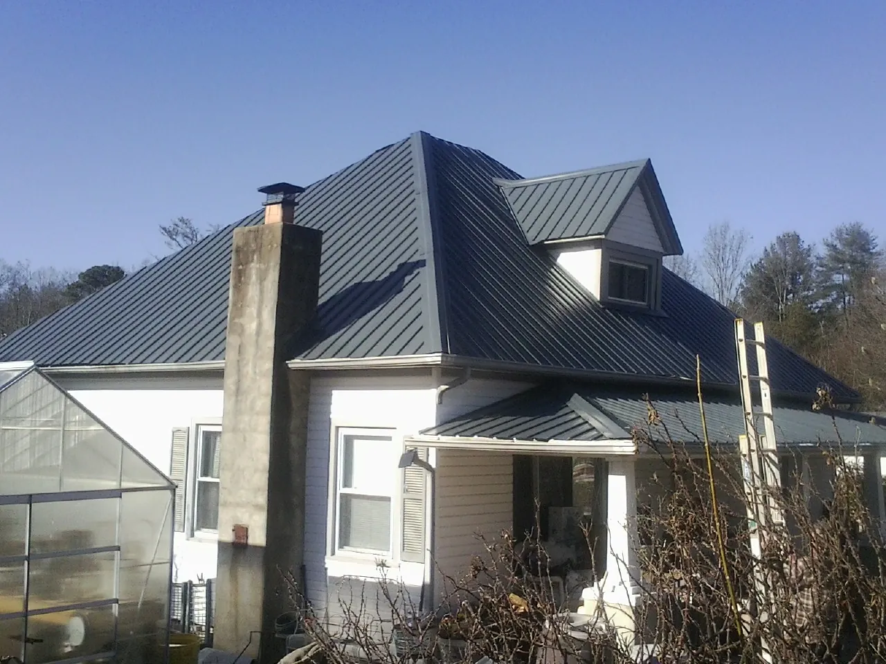Dark blue standing seam metal roof on a white farmhouse with dormer — Slate & Tile Roof Repair by Roofing Brothers in Montrose